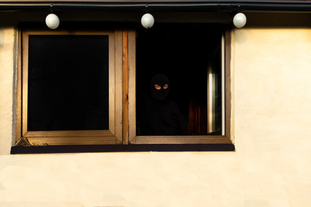 Thief in black cap covering face caught breaking into houseの写真素材