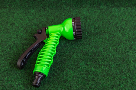 Green nozzle for watering placed on artificial grassの写真素材