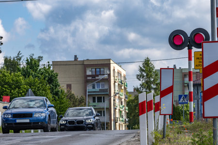 Cars pass through a railway crossing on a red light, damaged railway barriers at the crossing