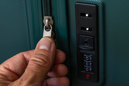 A traveler checks the zipper of his suitcase during airport check-inの写真素材