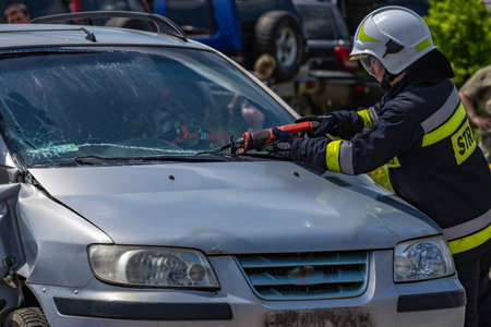 Firefighters use scissors to cut out the windshield of a passenger car that was involved in an accident.の写真素材