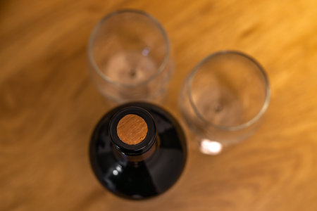 Top view of a cork-capped wine bottle and two empty glasses standing on a wooden boardの写真素材