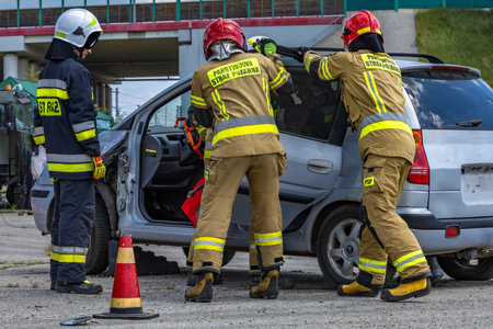 Firefighters cutting the body of a car after an accident, pulling a passenger out of the wrecked car, removing the door from the carの写真素材