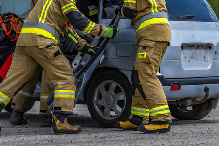 Firefighters cutting the body of a car after an accident, pulling a passenger out of the wrecked car, removing the door from the carの写真素材