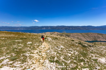 Panorama of the bay with the Vela Luka beach below, view of the beach from the top of the mountain, rocky trail leading to the picturesque beachの写真素材