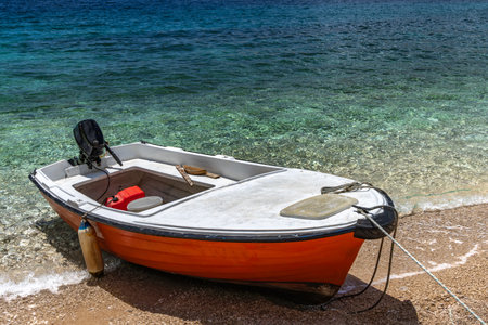 Jablanova Beach, orange fishing boat pulled up on the shore of an empty beach against the backdrop of the Adriatic Sea and Velebit Mountains on the island of KRK in Croatiaの写真素材