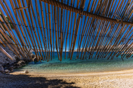 The most beautiful beach on the island of KRK Jablanova beach, straw sunshade, protection from the heat on an empty beachの写真素材
