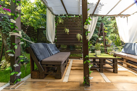 Construction of a wooden garden gazebo, a wooden pergola with white curtains, a relaxation area with...