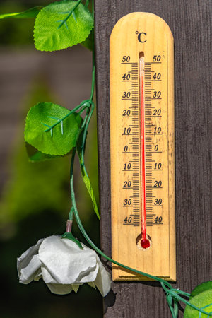 Wooden mercury thermometer showing very high temperature in summer on the front porch, a heat wave dangerous to healthの写真素材