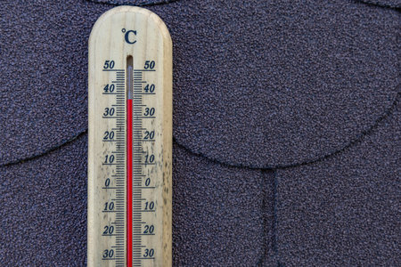 Measuring the temperature on the roof of the house, a wooden thermometer indicates an extremely high...
