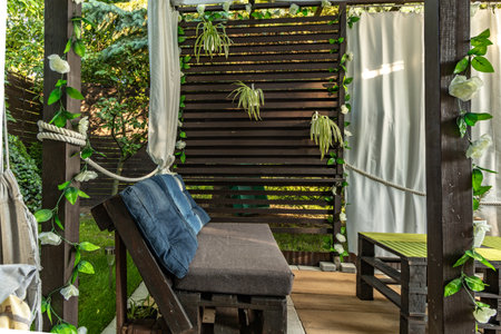 Homemade garden furniture from pallets, wooden veranda with curtains, terrace in front of the summer...