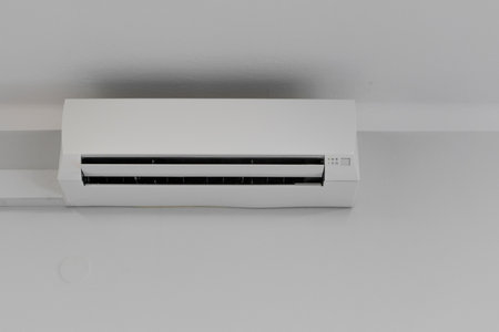 Air conditioning hanging high up from the ceiling on a white wall, damaged air conditioner,の写真素材