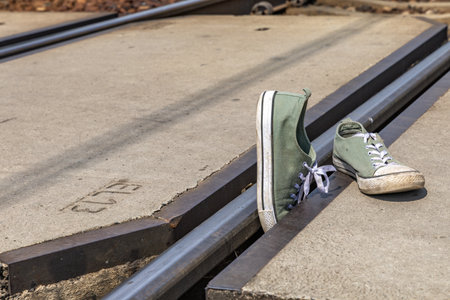 Green sports shoes by the tracks, a person hit by the tracks at a pedestrian crossing, an unguarded...