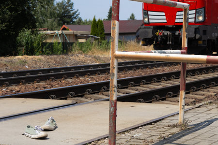 Scene on the tracks, train passing through an unguarded railway crossing, shoes by the tracks
