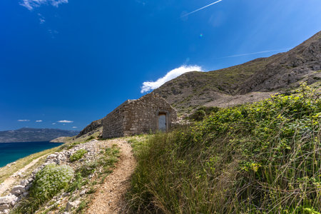 Panorama of the bay with the Vela Luka beach below, view of the beach from the top of the mountain, rocky trail leading to the picturesque beachの写真素材