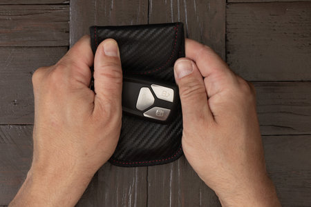 A man wraps his car keys in silver foil, trying to protect his car from theft by a thief, blocking the signal from the car alarm key.の写真素材
