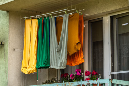 Colorful trousers, winter long johns, hanging on the balcony of a multi-family building, drying laundry at the stationの写真素材
