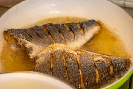 Two pieces of fresh fish fried in a pan, healthy food, fish seasoned with salt, deep fried