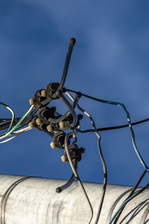 A cut power line, a broken power line, cut wires on a power pole, against a blue sky backgroundの写真素材