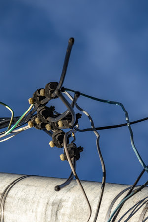 A cut power line, a broken power line, cut wires on a power pole, against a blue sky backgroundの写真素材