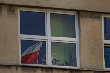 The flag of the Republic of Poland, the white and red flag on the roof of the office, the flag fluttering in the wind against the skyの写真素材