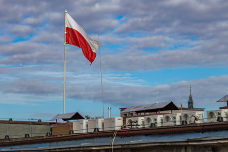 The flag of the Republic of Poland, the white and red flag on the roof of the office, the flag fluttering in the wind against the skyの写真素材