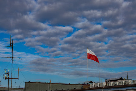 The flag of the Republic of Poland, the white and red flag on the roof of the office, the flag fluttering in the wind against the skyの写真素材
