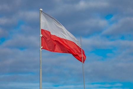 The flag of the Republic of Poland, the white and red flag on the roof of the office, the flag fluttering in the wind against the skyの写真素材