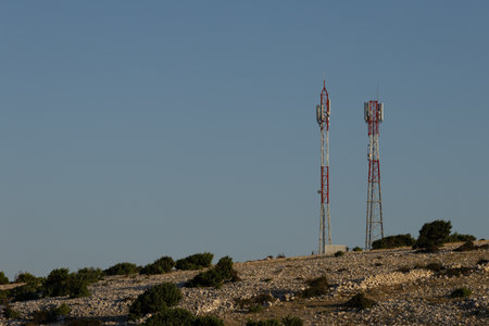 Two tall telecommunication antenna masts for broadcasting television and radio signals on a hill...