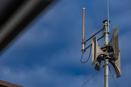An alarm siren mounted on the roof of a building, the siren emits a signal warning of an air raid in...