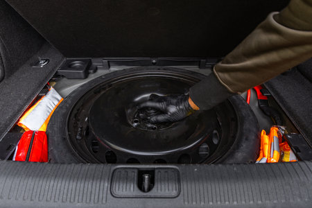 Taking the spare tire out of the trunk of the car, changing a flat tire on the highwayの写真素材