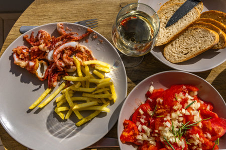 A delicious Mediterranean meal served on a wooden table, featuring crispy fried calamari with French...