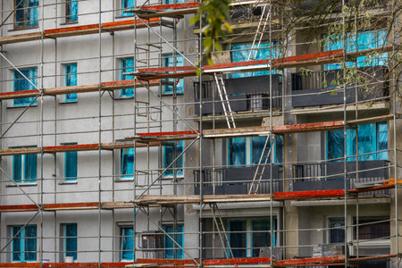 Aluminum scaffolding installed on the facade of a tall building, walls insulated with Styrofoam,...