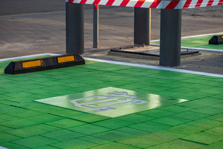 Green-painted parking spot designated for electric vehicles with EV and charging symbol on the pavement. Concept of sustainable transport, eco mobility, and modern city infrastructure.の写真素材