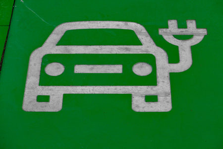 Green-painted parking spot designated for electric vehicles with EV and charging symbol on the pavement. Concept of sustainable transport, eco mobility, and modern city infrastructure.の写真素材