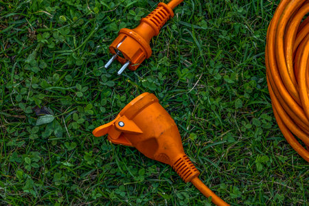 An electric extension cord lying on a green lawn in a garden, representing connection, harmony, and modern outdoor design. Concept of energy, unity, and sustainable living.の写真素材