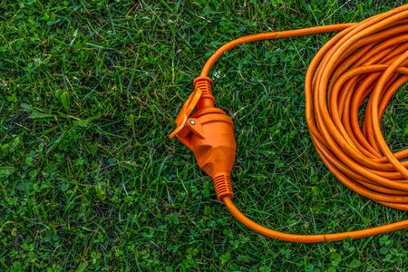 An electric extension cord lying on a green lawn in a garden, representing connection, harmony, and modern outdoor design. Concept of energy, unity, and sustainable living.の写真素材
