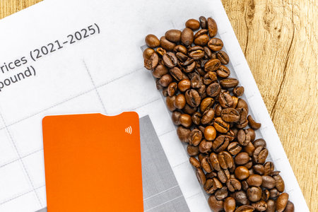Top view of roasted coffee beans and printed chart showing rising global coffee prices on wooden table.の写真素材