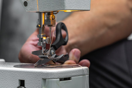 Close-up of hands sewing lightweight fabric on a sewing machine at home. Concept of handicraft,...