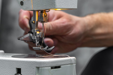 Close-up of hands sewing lightweight fabric on a sewing machine at home. Concept of handicraft,...
