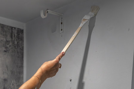 Smiling blonde woman painting wall white with brush during home renovation. Concept of diy project, interior design, home improvement, renovation work and creative lifestyle.の写真素材