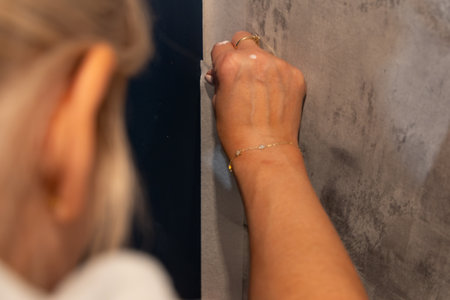 Smiling blonde woman painting wall white with brush during home renovation. Concept of diy project, interior design, home improvement, renovation work and creative lifestyle.の写真素材