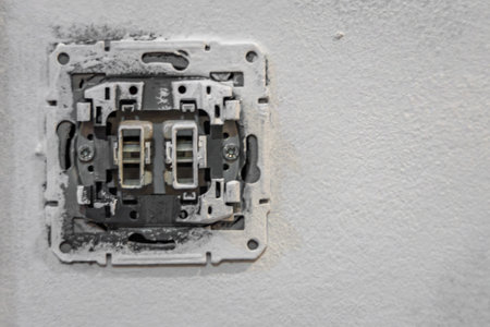 Close up of dismantled electrical light switch wiring without cover plate on wall during home renovation. Concept of electricity repair, maintenance, power installation and DIY work.の写真素材