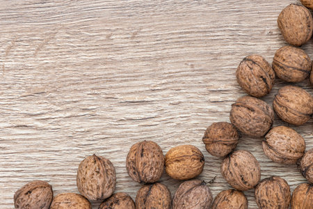 Autumn walnuts in shell arranged on a wooden board, autumn background for a postcardの写真素材