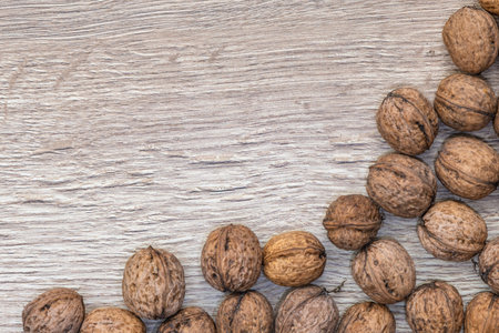 Autumn walnuts in shell arranged on a wooden board, autumn background for a postcardの写真素材