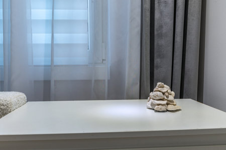 Decoration made of white stones brought from Croatia glued together in a stack arranged on a white nightstand under the window in the living room of an apartment in a block of flatsの写真素材
