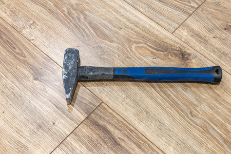 A blue nail hammer placed on the floor during renovation, vinyl plank flooring.の写真素材