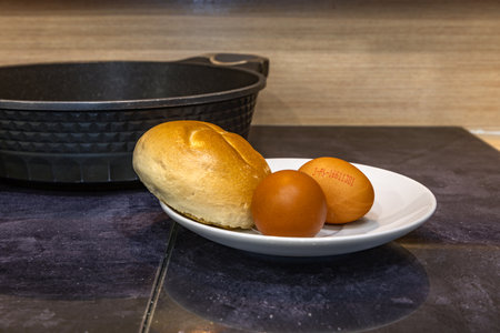 A dry roll and two eggs placed on a plate, preparing a simple breakfast