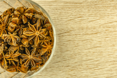 Star anise poured into a glass container, tea spice on a wooden table, warming drinkの写真素材