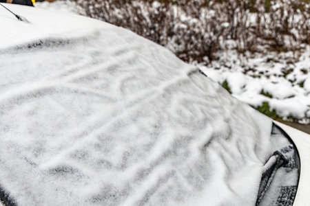 Snow on the car window, a tarpaulin on the windshield to protect against snow, a car window covered with snowの写真素材